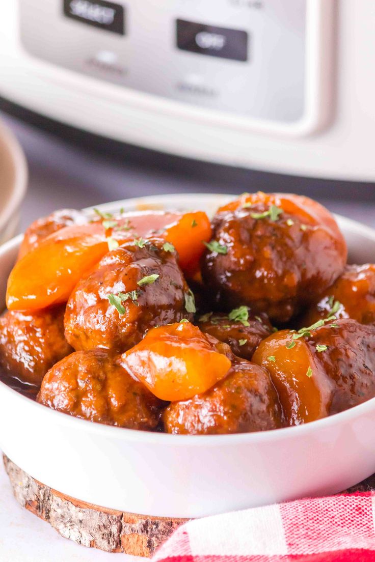 a white bowl filled with meatballs and carrots next to an instant pressure cooker