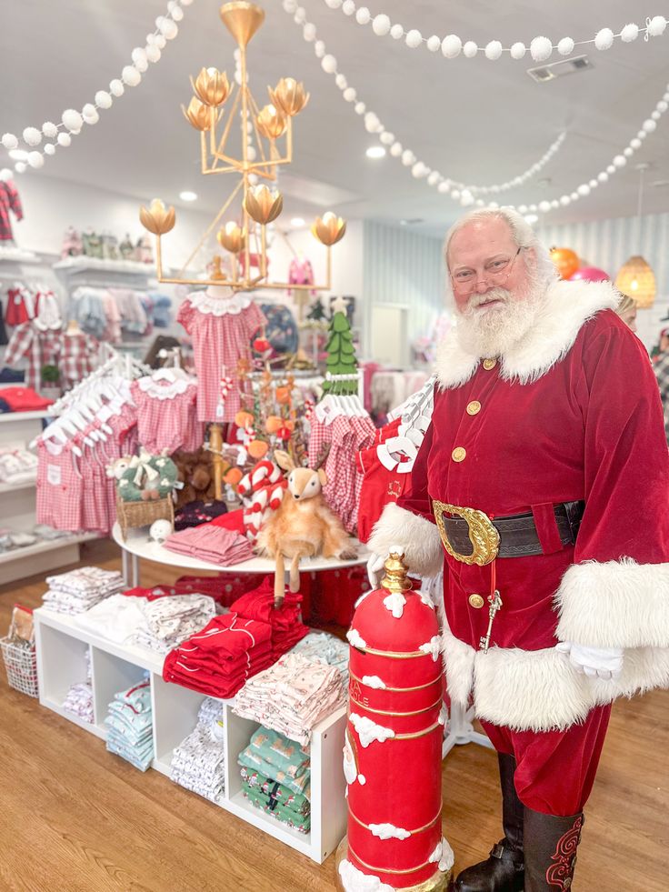 a man dressed as santa claus standing next to a red fire hydrant in a store