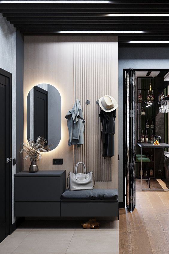 a black and white room with clothes hanging on the wall next to a bench, mirror, coat rack and door