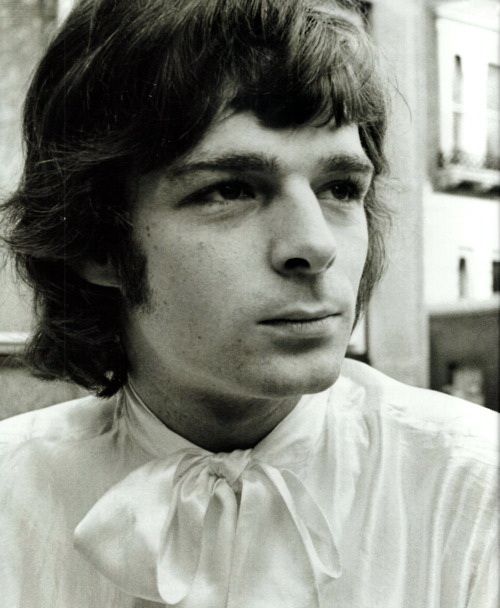 a black and white photo of a man with long hair wearing a shirt and tie