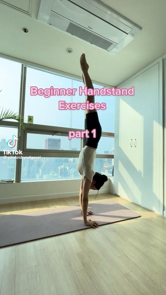 a person doing a handstand on a yoga mat in front of a window