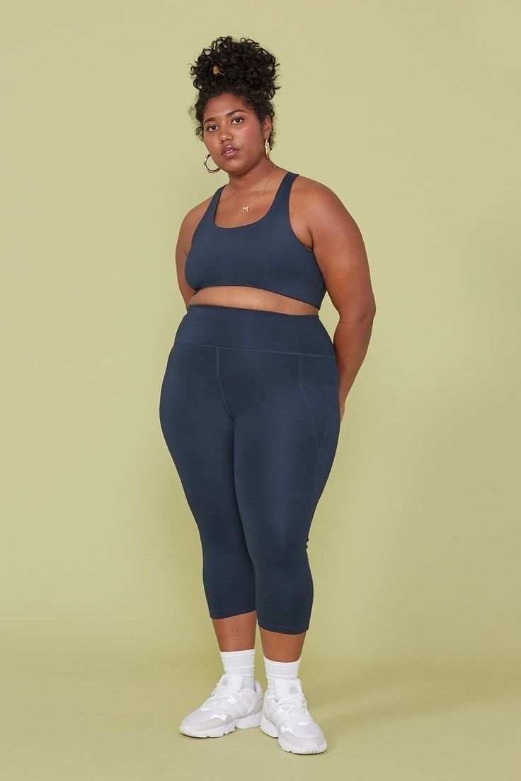 a woman in a blue sports bra top and leggings poses for the camera