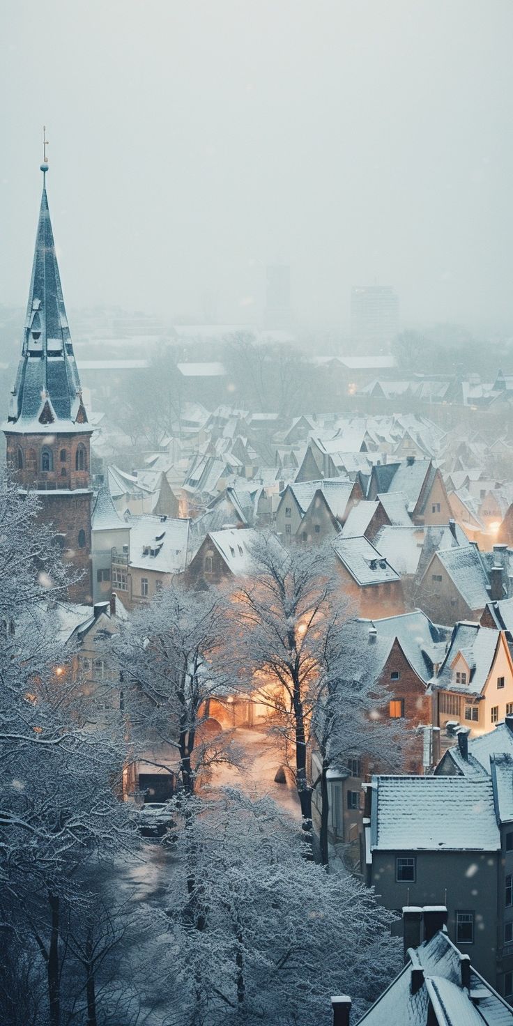 a snowy city with buildings and trees in the foreground