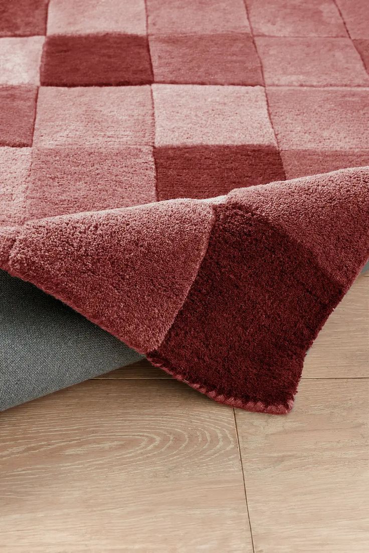 a red and grey rug on top of a wooden floor