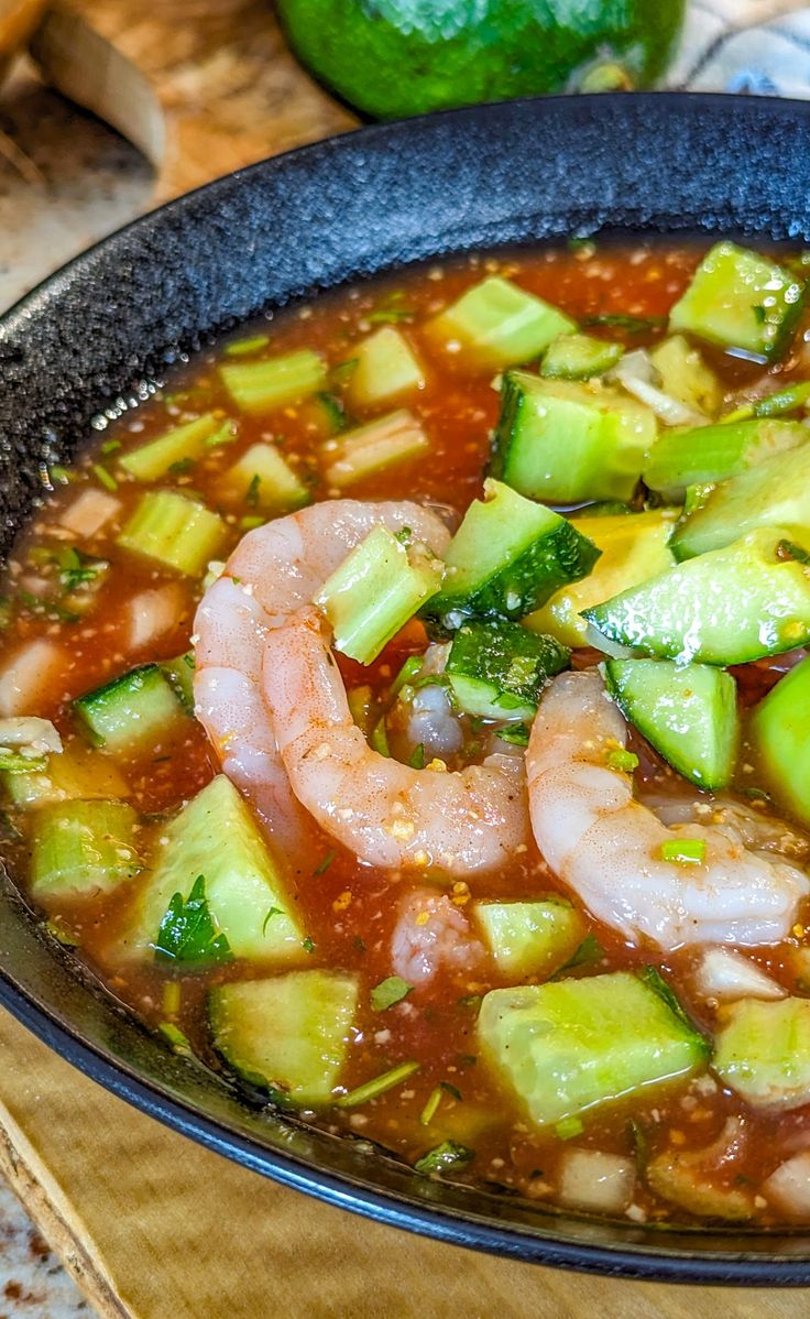 a bowl of soup with shrimp, zucchini and broccoli