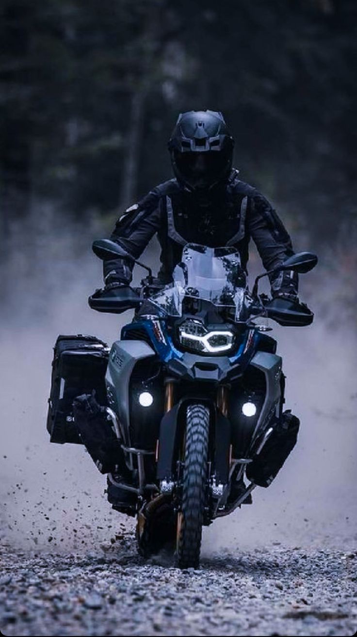 a man riding on the back of a motorcycle down a dirt road