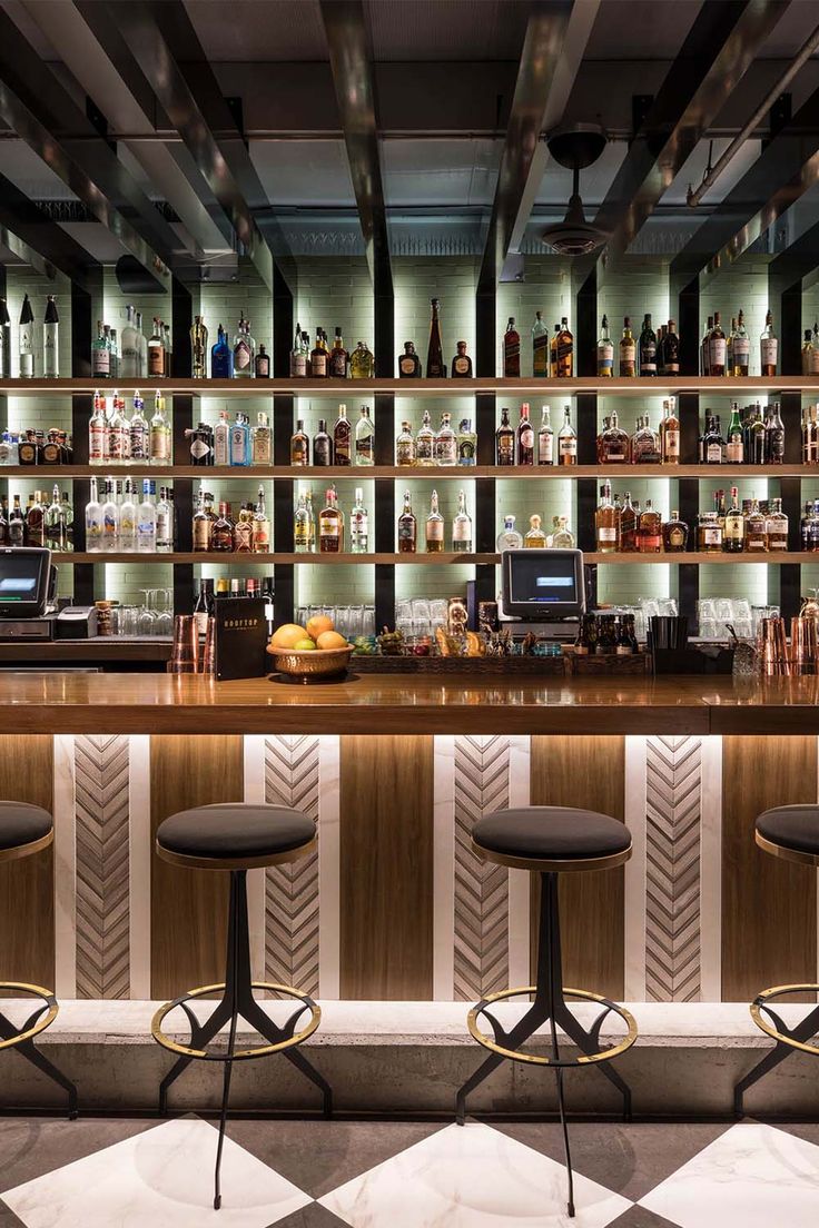 three stools in front of a bar with liquor bottles on the shelves behind it