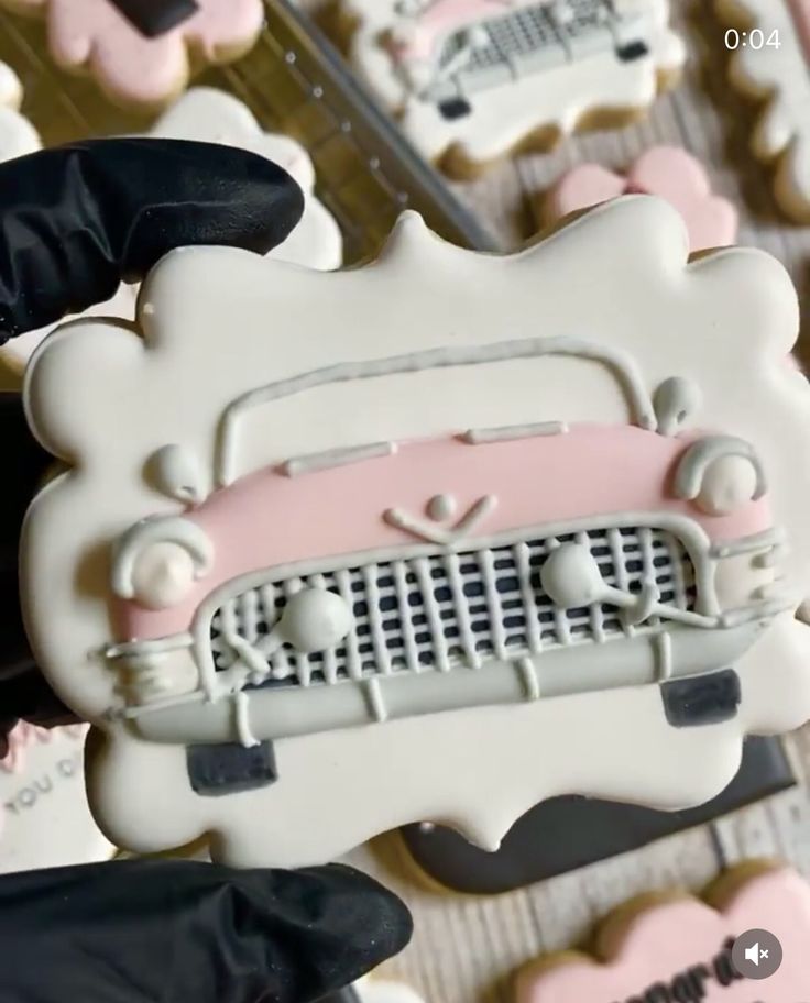 decorated cookies in the shape of cars are displayed on a table with pink and white frosting