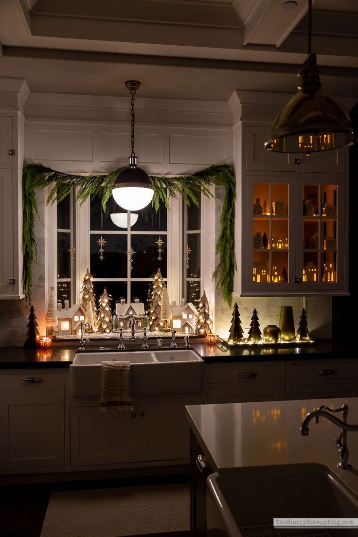 a kitchen decorated for christmas with candles and greenery on the window sill above the sink