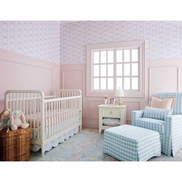 a baby's room with pink walls, blue and white furniture and a teddy bear