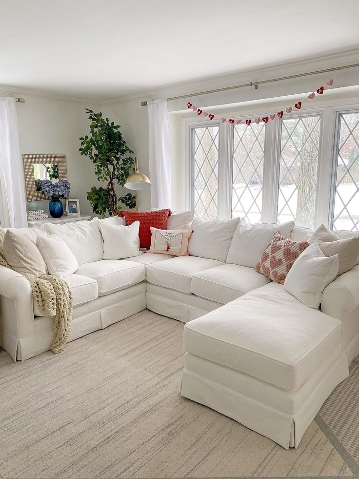 a living room filled with white furniture and lots of pillows on top of it's couches