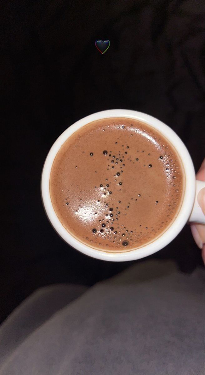 a person is holding a cup of hot chocolate