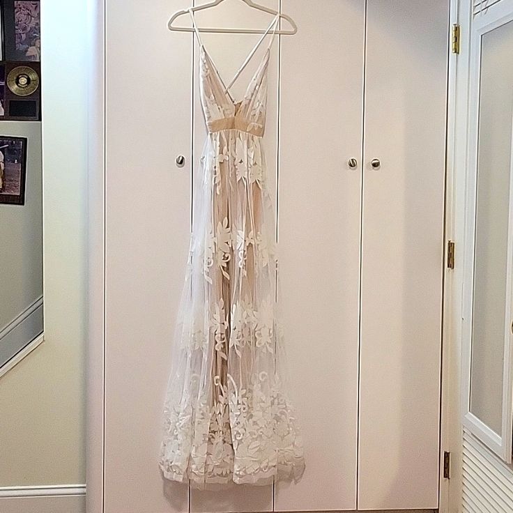 a white dress hanging on a hanger in a room with two doors and pictures on the wall