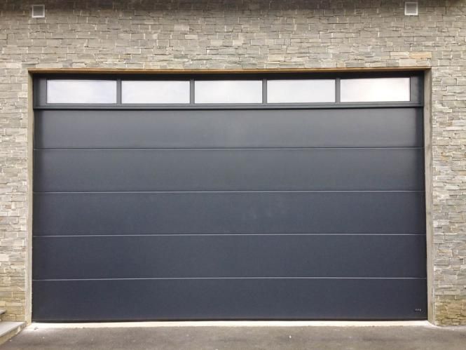 a grey garage door in front of a brick building