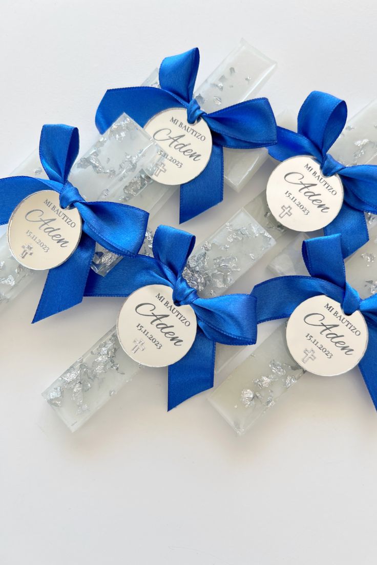 three blue ribbons with name tags on them are tied to clear acrylic blocks