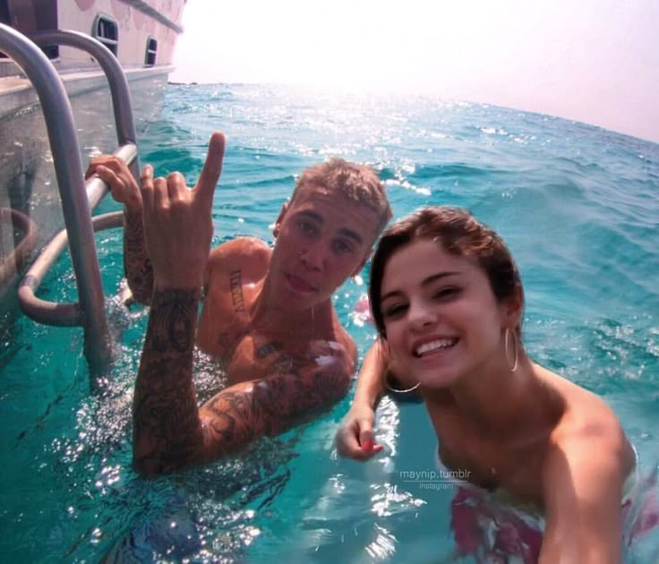 the man and woman are in the water posing for a selfie with their hand up