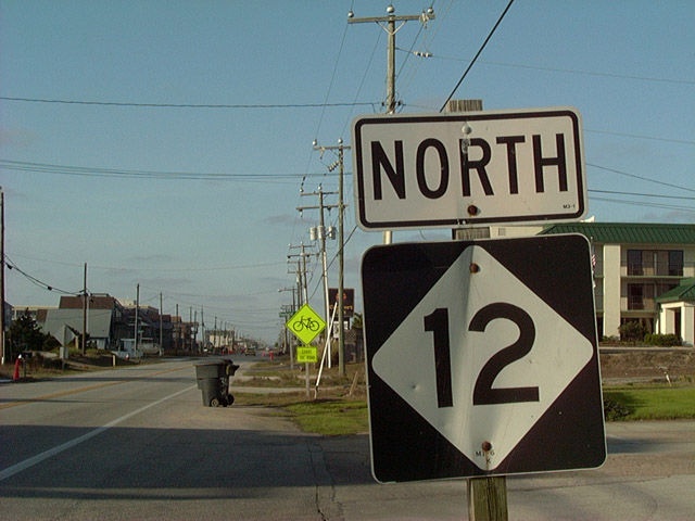 a street sign that says north and 12 is on the side of the road with houses in the background