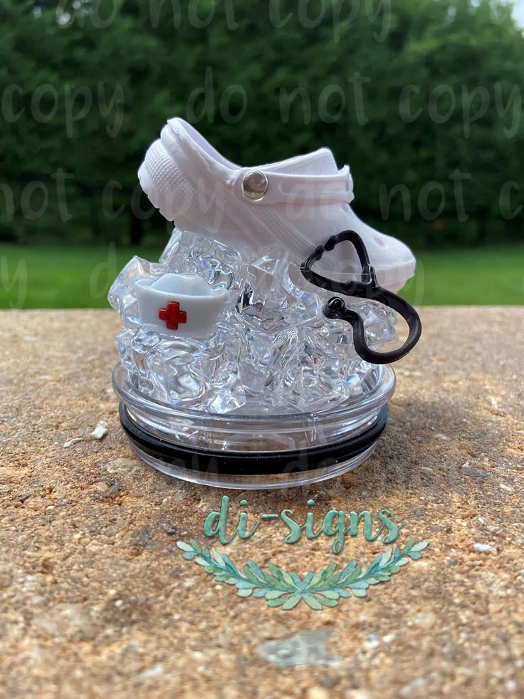 a pair of white sneakers sitting on top of a pile of ice cubes in front of trees