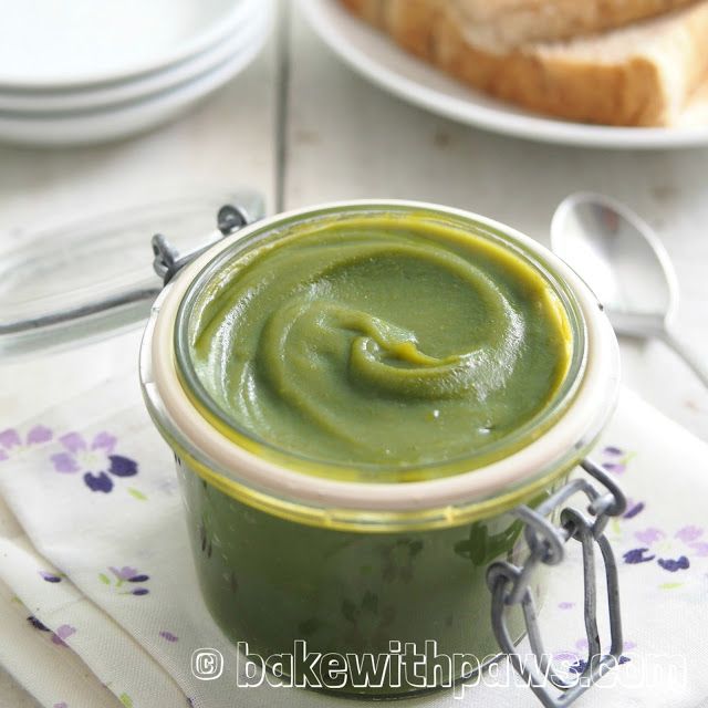 a jar filled with green liquid sitting on top of a table next to some bread