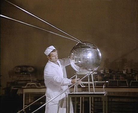 a man in white suit holding a large metal object on top of a metal pole