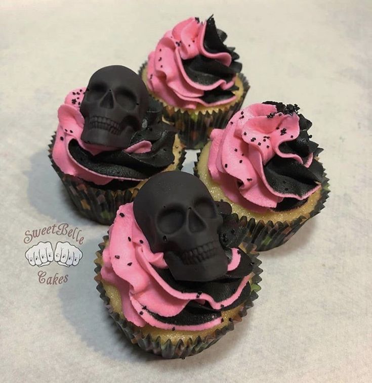 three cupcakes with pink frosting and black icing decorated with skull heads