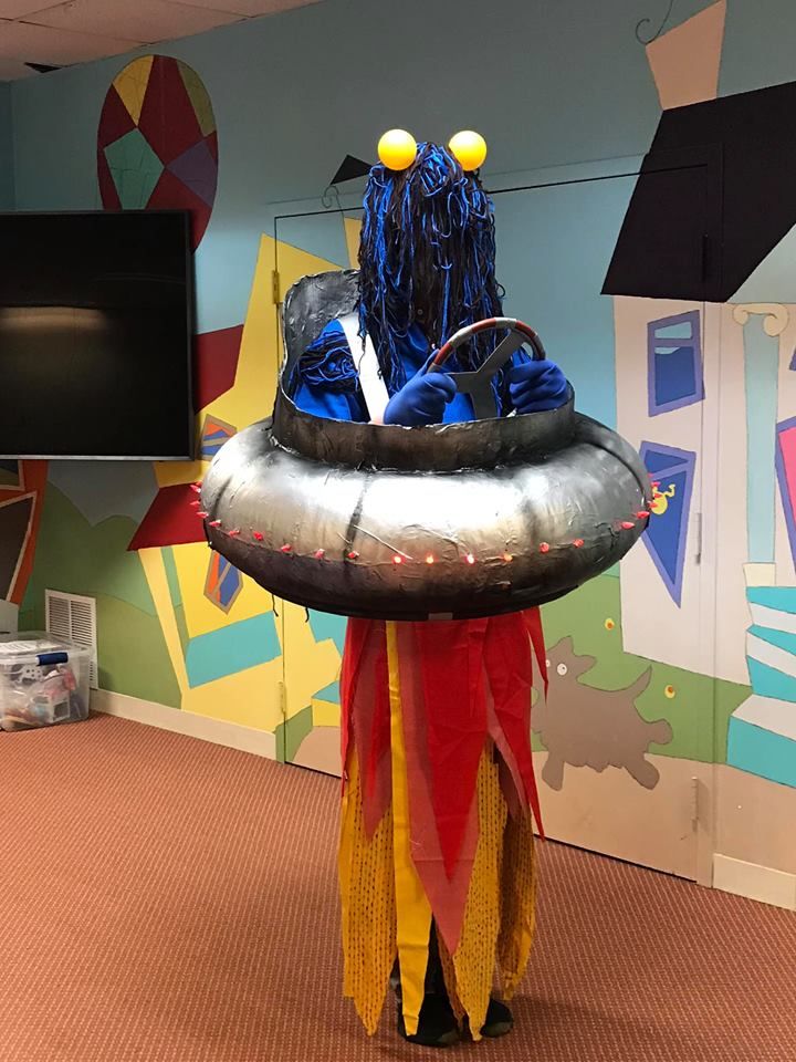 an inflatable costumed person standing next to a television