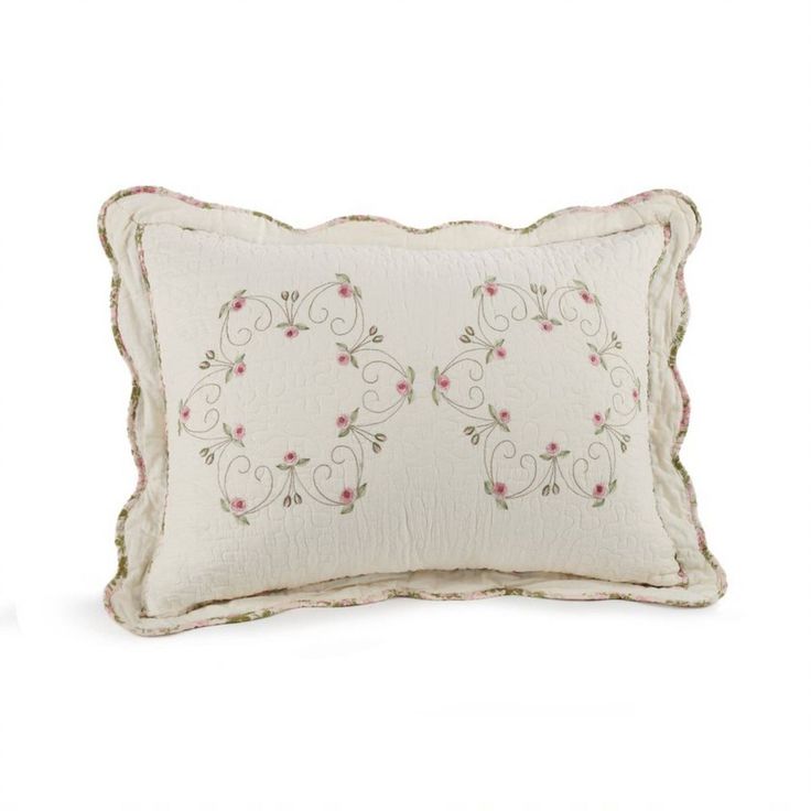 a white pillow with pink flowers on the front and back, sitting on a white surface