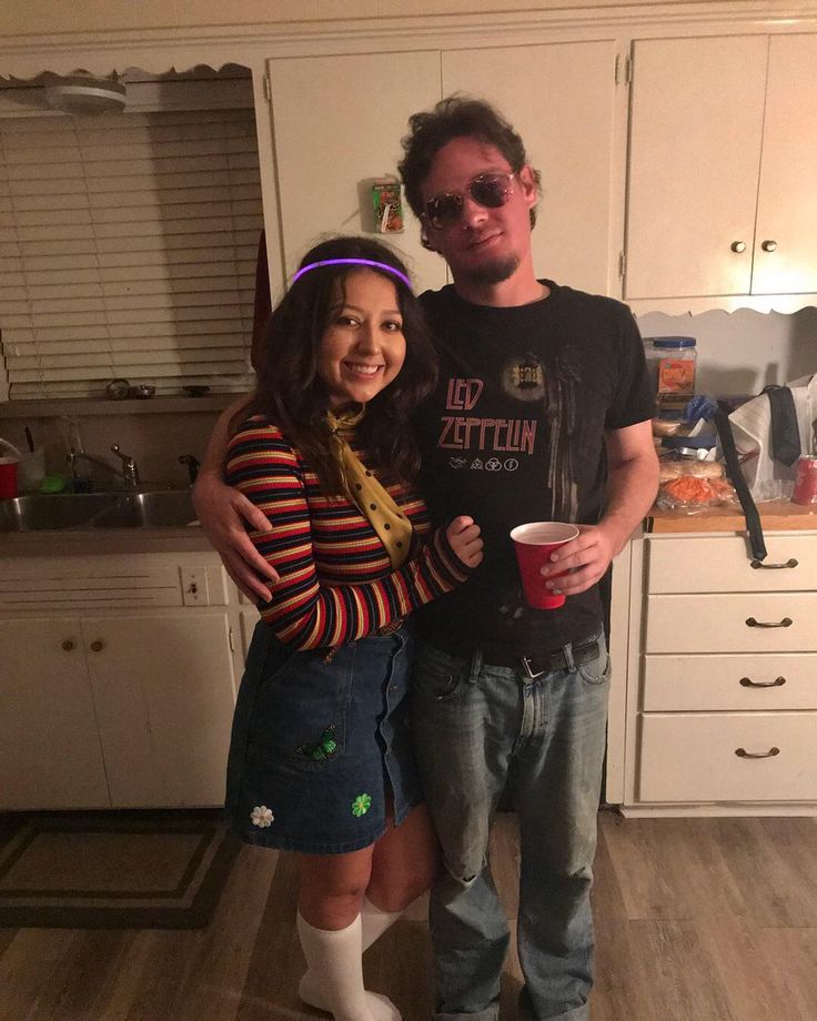 a man standing next to a woman in a kitchen holding a cup and smiling at the camera