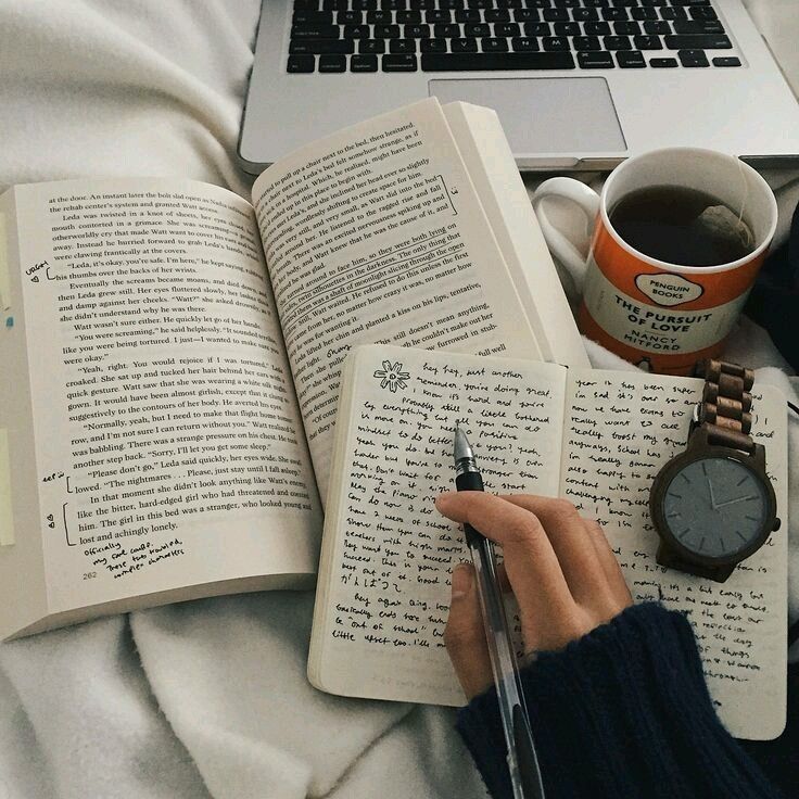 an open book with writing on it next to a cup of coffee and a watch