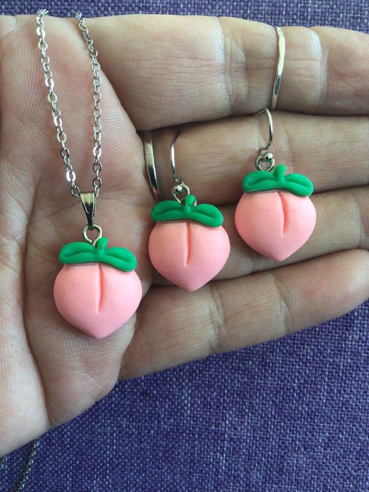 two necklaces made to look like strawberrys are being held in someone's hand