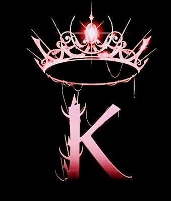 the letter k with a crown on top of it is lit up in pink light