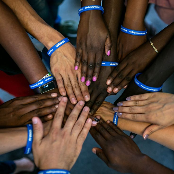 a group of people holding their hands together in a circle with blue bands around them