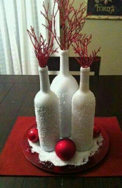 three wine bottles are decorated with red ornaments and snow on the base, along with two christmas balls