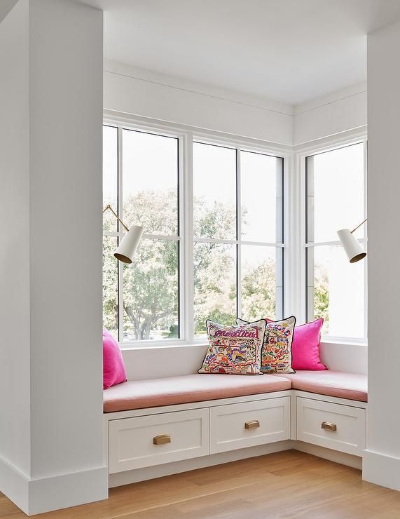 a white window seat with pink pillows on it