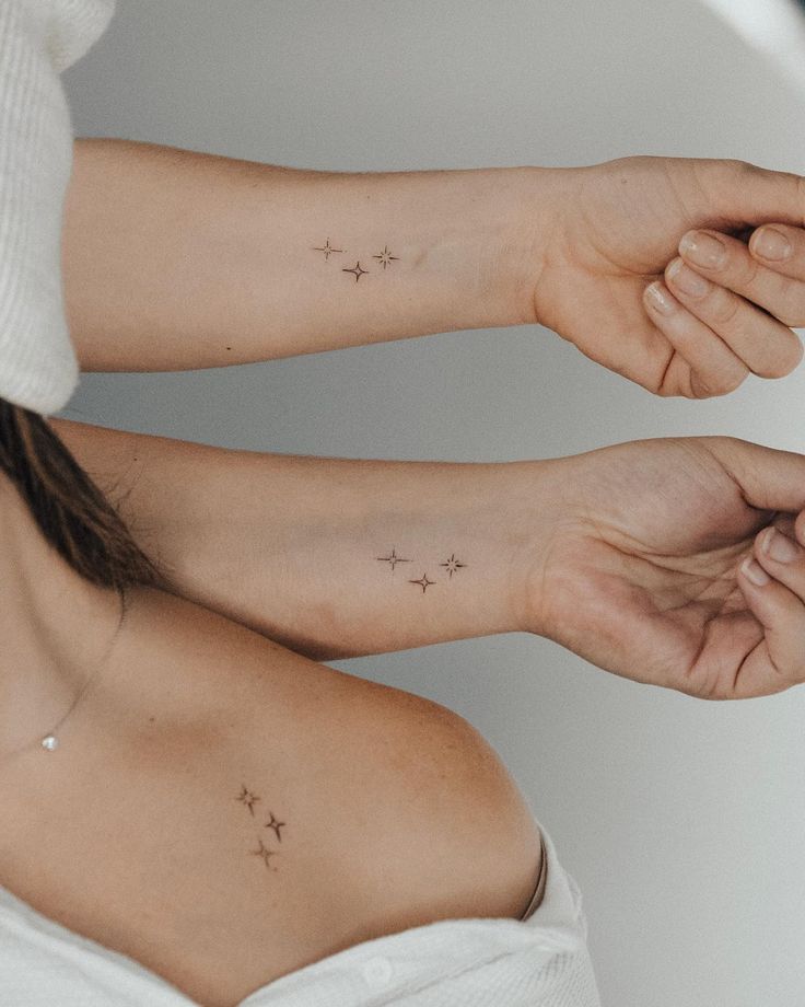 two women with matching tattoos on their arms, both holding hands up to each other