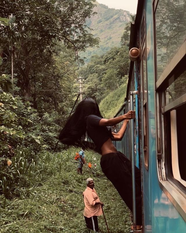 a woman leaning on the side of a train as another person stands next to her