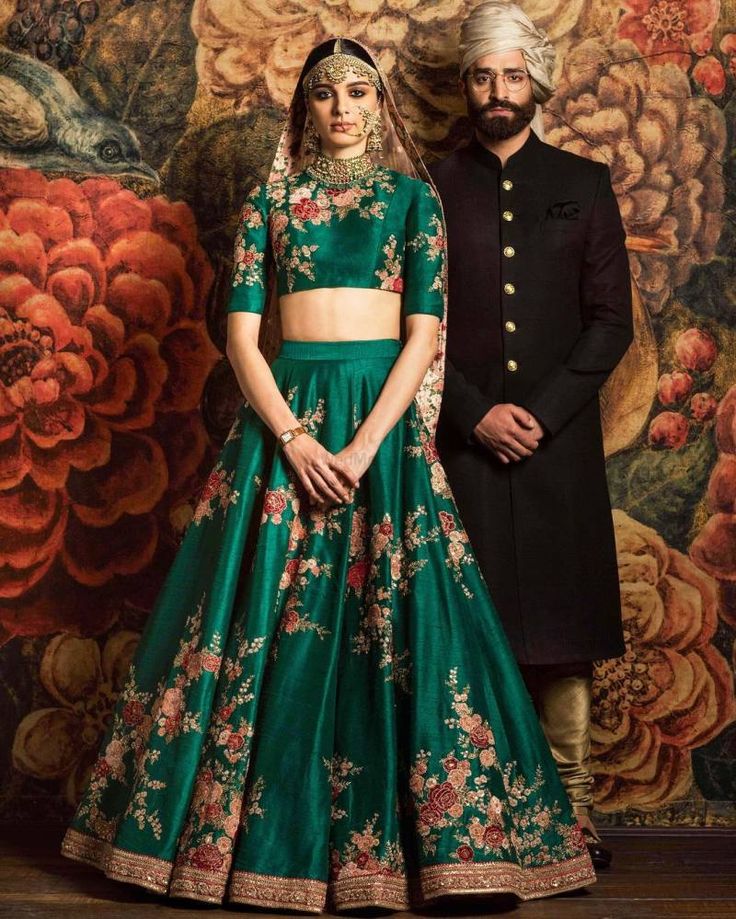 a woman in a green and gold lehenga with flowers on the skirt, crop top