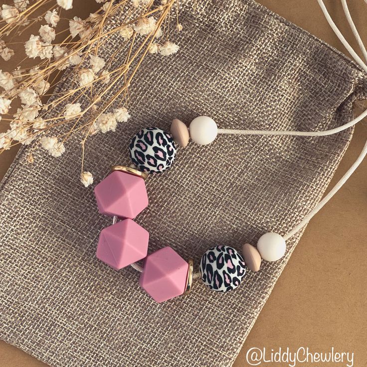 three pink and white beads with leopard print on them next to some dried flowers in the background