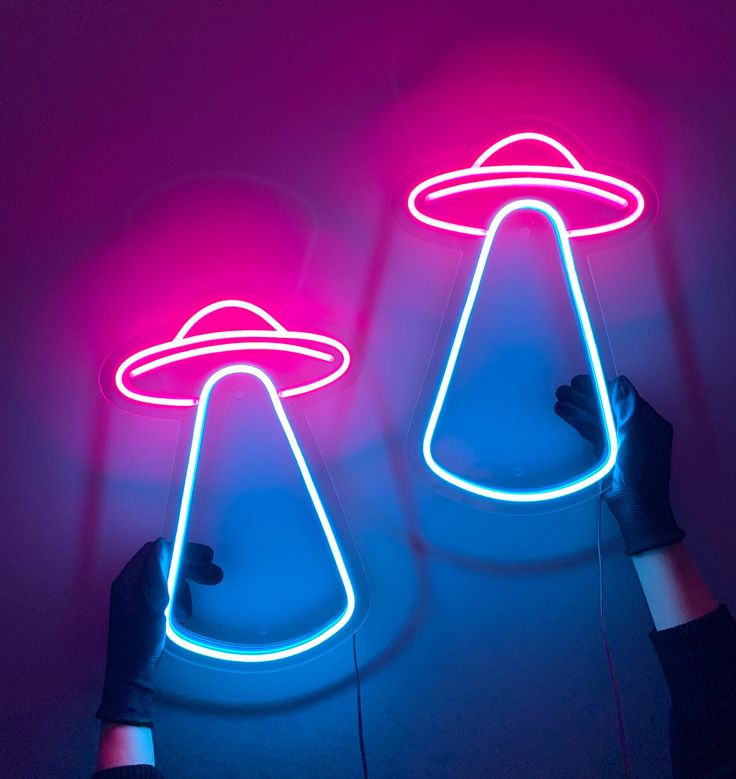 two neon lights that look like alien hats are being held by someone's hands