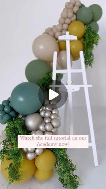 a ladder with balloons and greenery on it