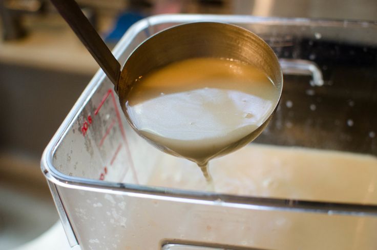 a ladle full of liquid being poured into a pan