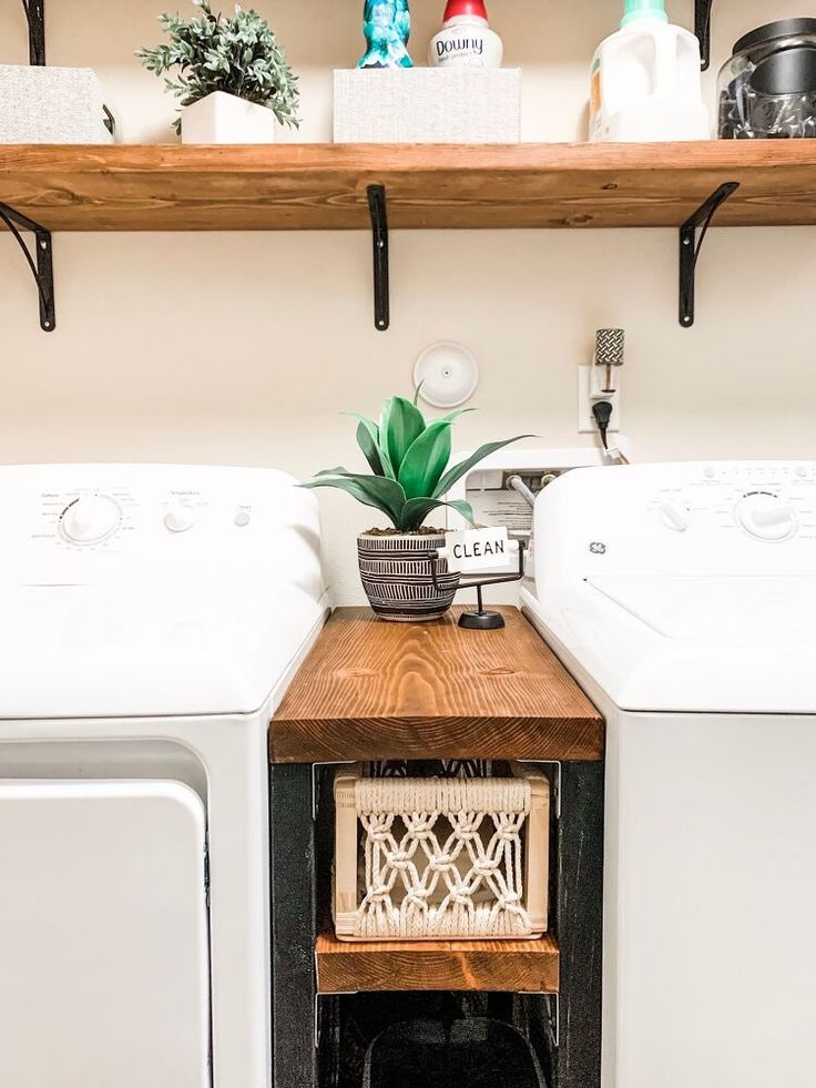 a washer and dryer sitting next to each other in a room with wooden shelves