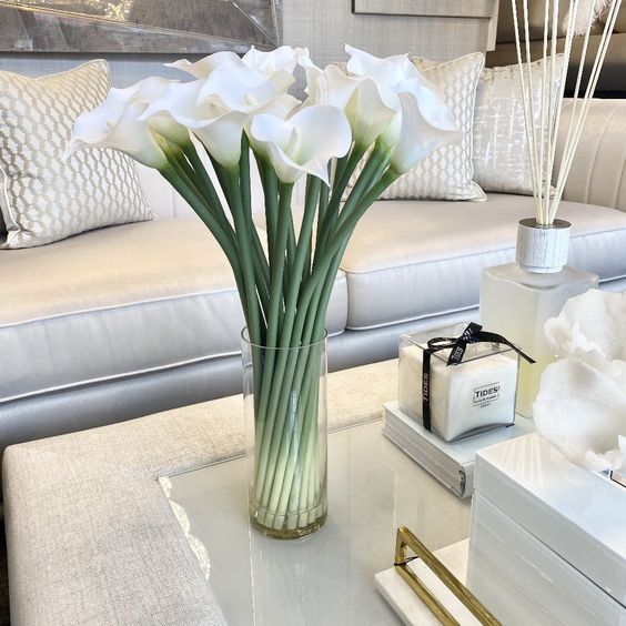 white flowers are in a vase on a coffee table