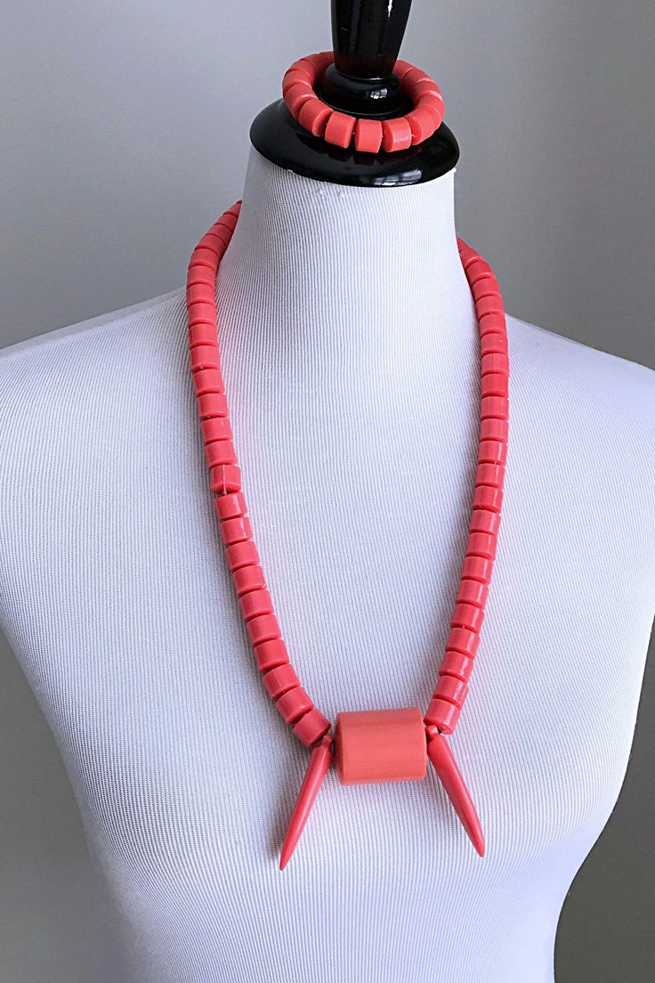 This is a traditional West African beaded necklace. These jewelry pieces are unisex and are designed to be worn by adults Beads are made of plastic Length ( from neck to chest): 15 inches Come with one (1) elastic bracelet These coral orange beaded jewelry is an integral part of West African culture. Traditionally it is worn by Royalty, Chiefs, and those who are part of the Royal households among many kingdoms in West Africa. It is also worn by brides and grooms during their wedding ceremonies, Adjustable Hand-strung Orange Necklaces, Adjustable Hand-strung Orange Necklace, Plastic Round Beads Necklace For Gift, Adjustable Orange Necklace With Wooden Beads, Adjustable Coral Necklace With Large Beads, Adjustable Orange Necklace With Spacer Beads, Adjustable Orange Single Strand Beaded Necklace, Plastic Beaded Necklace With Round Beads, Adjustable Coral Necklace With Colorful Beads