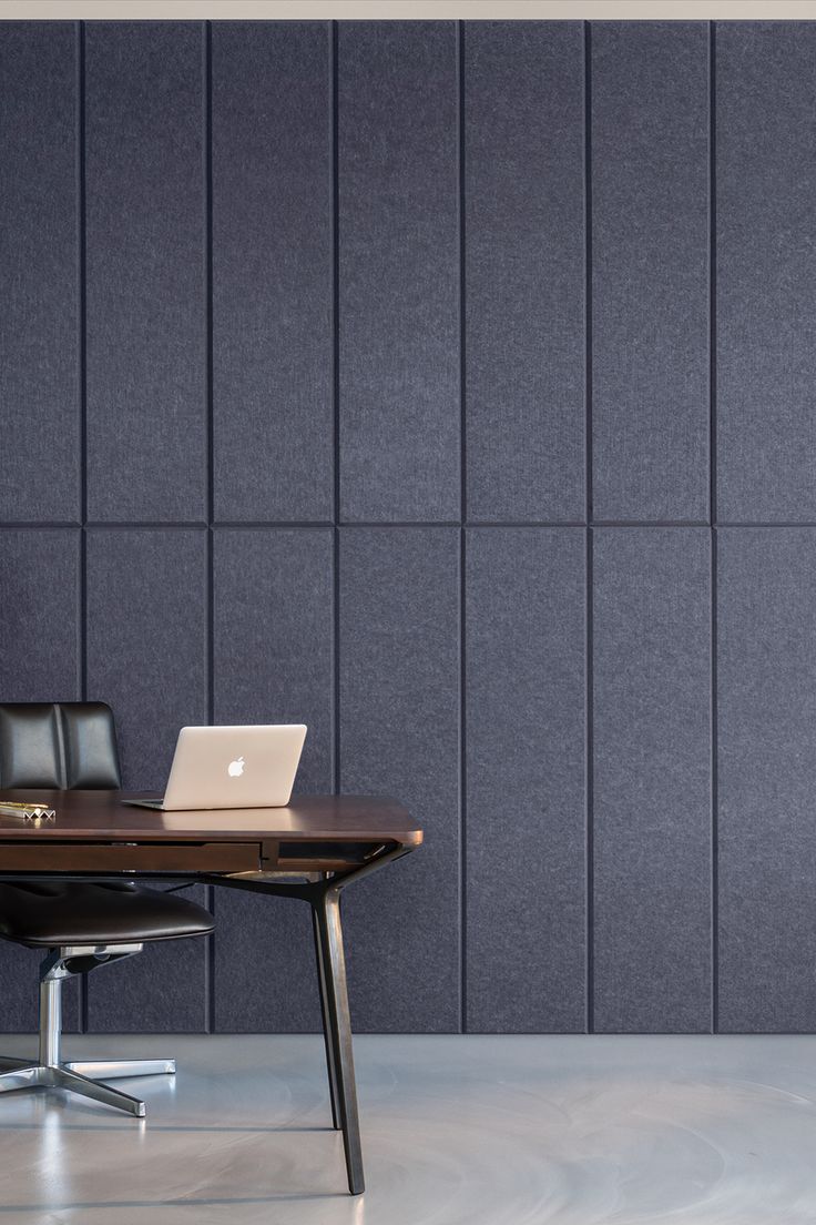 a laptop computer sitting on top of a wooden desk in front of a gray wall