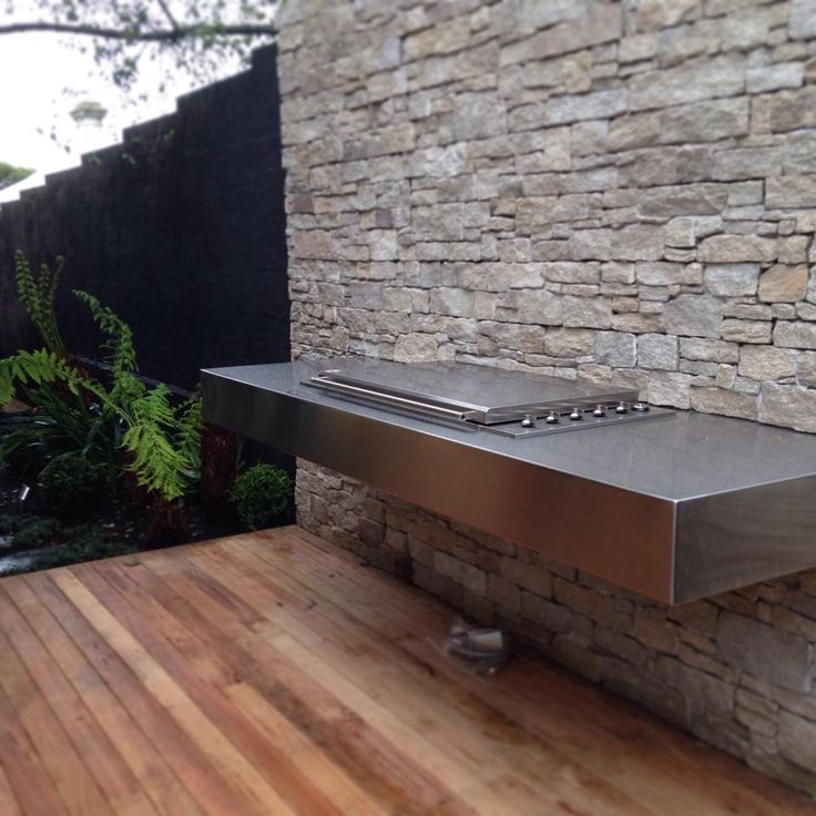 a stainless steel table sitting on top of a wooden floor next to a stone wall