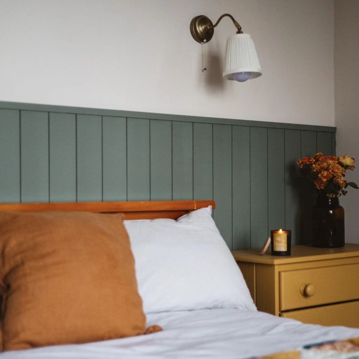 a bed with two lamps on the wall above it and a night stand next to it