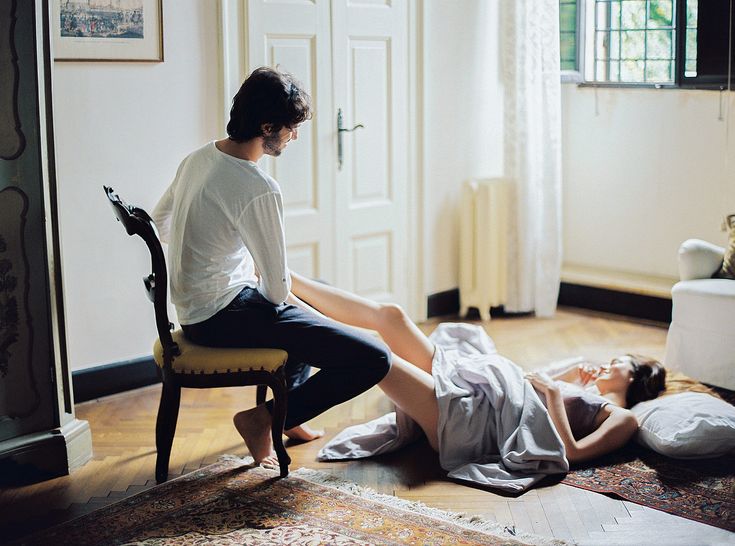 a man sitting on the floor next to a woman laying on the ground in front of a chair