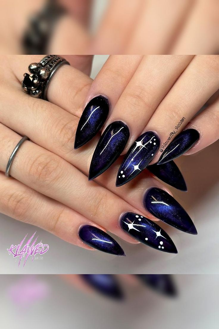 Step into the stellar realm with these mesmerizing cat eye effect stiletto nails. A dark and dramatic black base coated with a captivating deep blue metallic hue creates a celestial aura. The addition of delicate white stars on select accent nails adds a touch of cosmic elegance. Prepare to captivate with these stunning celestial-inspired stiletto nails. ✨💅🌌 // Photo Credit: Instagram @klawedby_kristen Celestial Cat Eye Nails, Black Blue Nail Designs, Black And Blue Cat Eye Nails, Blue Galaxy Nails, Galaxy Cat Eye Nails, Cat Eye Galaxy Nails, Dark Blue Cat Eye Nails, Blue Celestial Nails, Dark Blue Stiletto Nails