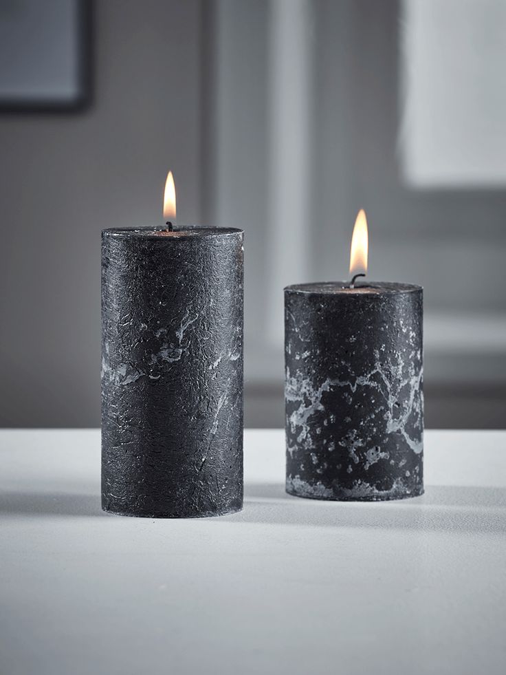 two black candles sitting next to each other on a table